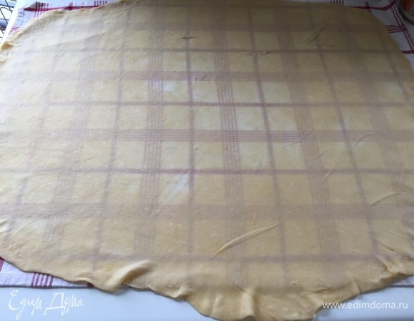 Теперь раскатываем тесто смазанной маслом скалкой как можно тоньше. А уж потом вытягиваем тесто двумя руками, двигаясь от центра к краям. Тесто должно быть настолько тонкое, чтоб рисунок полотенца под ним просвечивался.