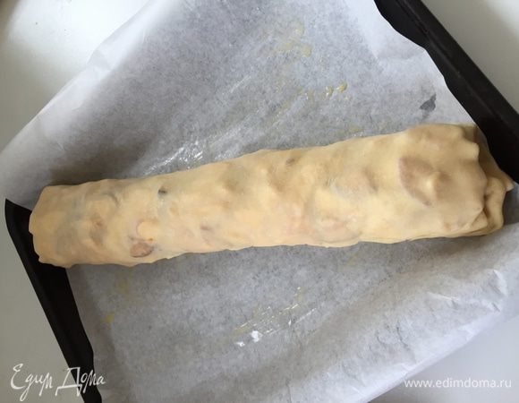 Потом подгибаем края вовнутрь и скручиваем плотный рулет, помогая себе полотенцем. Выкладываем штрудель на противень.