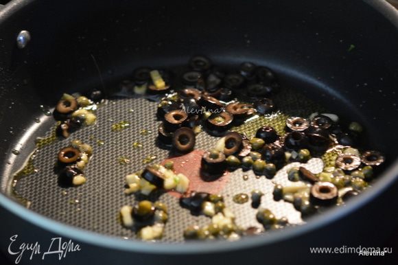 Разогреть оливковое масло. Добавить очищенный и нарезанный чеснок, каперсы, оливки желательно каламата. Готовить примерно 2 мин.