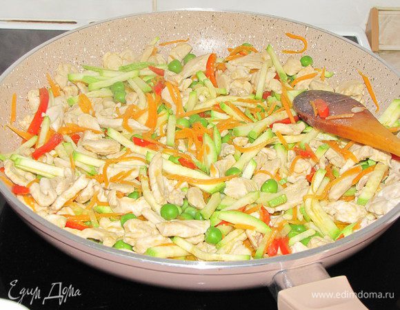 Добавить к мясу нарезанные овощи и зеленый горошек (если замороженный, то предварительно разморозить), мелко рубленный чеснок.