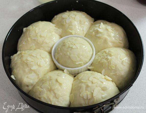 Накрыть и оставить подниматься на 30 минут. Затем смазать яичным желтком с молоком и посыпать миндальными хлопьями.