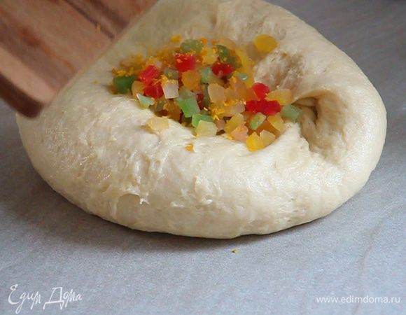 Делаем в тесте воронку и в нее высыпаем цукаты и цедру апельсина. Закрываем воронку тестом с краев и вымешиваем, чтобы цукаты и цедра равномерно распределились по всей массе.