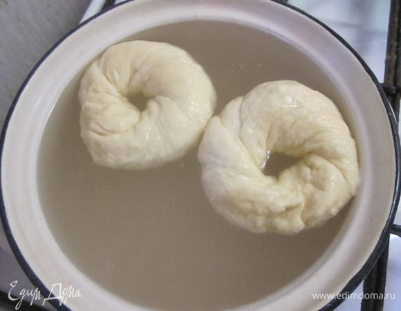 В кастрюлю налить 1,5 литра воды, довести до кипения, всыпать соду, уменьшить огонь. Аккуратно опускать бублики на 30-40 секунд в воду.