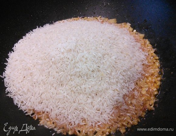 Добавляем рис, перемешиваем, чтобы рис смешался с маслом, обжариваем 1 минуту.