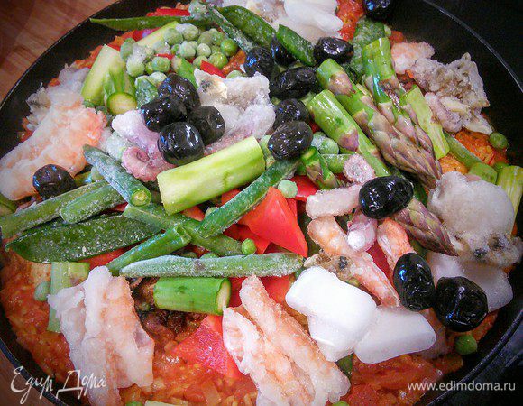 Через примерно 10 мин добавляем овощи, маслины и морепродукты (у меня тоже замороженные). Солим и перчим. Перемешиваем. Тушим под крышкой еще 10-15 минут, до готовности риса и мяса.