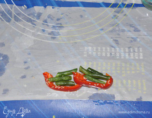 С тестом фило надо работать очень быстро, т.к. оно быстро сохнет. Листы, с которыми не работаете надо прикрывать влажным (но не мокрым!) полотенцем. 
Из каждого листа теста фило будем крутить по 2 палочки. Лист фило разрезать пополам — получится 2 прямоугольника, размером около 20 на 30 см.
Кисточкой смазать листы смесью из растительного масла и воды. Тесто станет еще более податливым и легко можно приготовить рулеты.
Вдоль длинной стороны теста, чуть отступив от края, положить пару брусочков перца, фасоль...
 