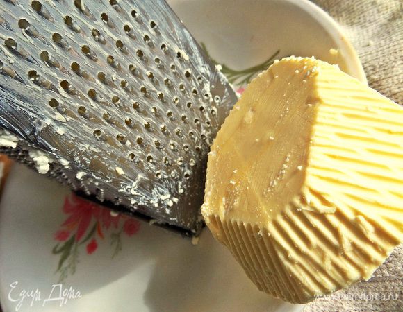 Убираем бумажную упаковку и прямо в руках натираем масло на мелкой терке после творога.