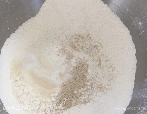 Муку просеиваем, всыпаем дрожжи, сахар, соль. Хорошо перемешиваем.