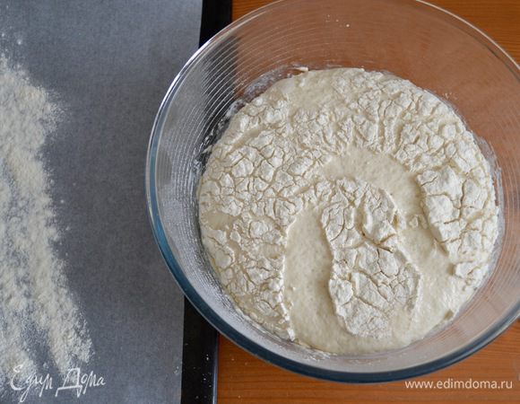 Через полтора часа тесто значительно увеличилось в объеме. На противень положить лист пекарской бумаги и присыпать его немного мукой в том месте, где будем формировать хлеб.