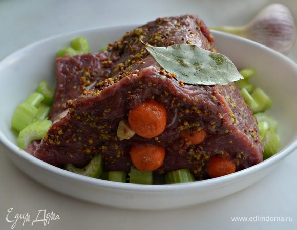 Посолите говядину и натрите перцем и горчицей. Затем с помощью ножа сделайте надрезы и нашпигуйте мясо дольками чеснока и морковью. Уложите мясо в форму, смазанную растительным маслом. Вокруг уложите нарезанные кусочки сельдерея, лавровый лист. Накройте кусок мяса фольгой и запекайте в разогретой до 170°С духовке около 1,5 часов, периодически поливая мясо выделившимся соком.