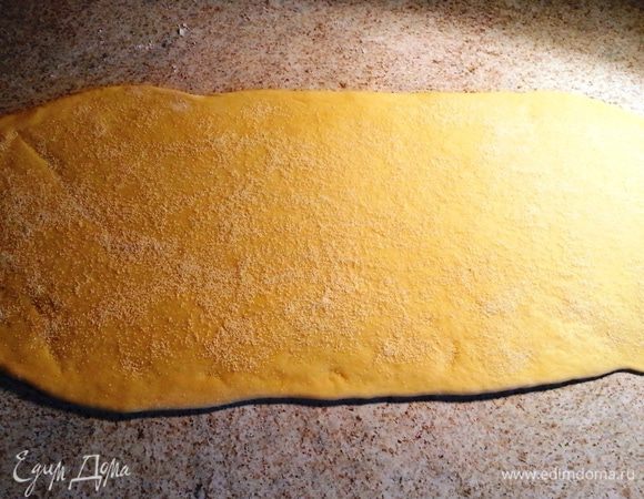 Одну часть раскатать в прямоугольник (получается примерно 23х50 см). На тесто посыпать неполную столовую ложку манной крупы. Манка впитает лишнюю жидкость.