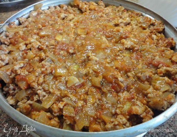 Сверху выложить готовый фарш с соусом. И запекать в духовке при температуре 210°C 15 минут. Затем посыпать оставшимся сыром и еще запекать 10 минут.