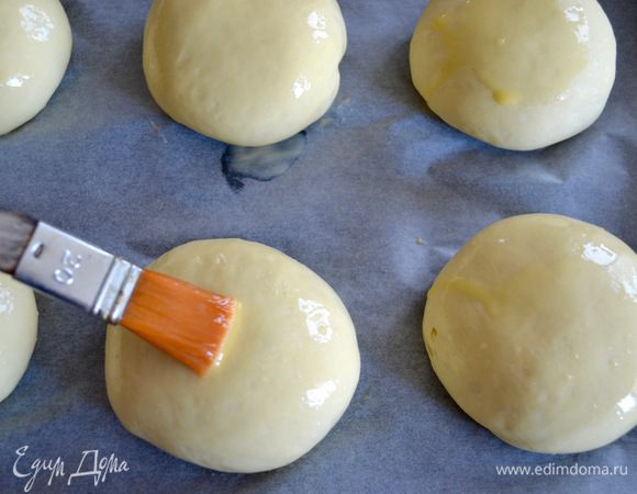 Духовку разогреть до 200°C. Яйцо смешать с водой и взболтать. Смазать булочки яичной смесью и присыпать кунжутом (по желанию).