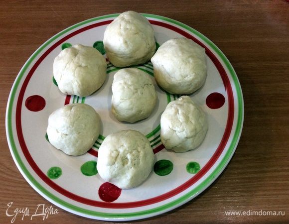 Делаем из теста 7 шариков, 2 из которых должны быть большего размера, а 5 — меньшего. Высыпаем немного муки на стол и начинаем раскатывать каждый шарик при помощи скалки на тоненькие лепешки по размеру формы для выпекания. 