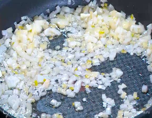 Разогреть в сковороде со съемной ручкой оливковое масло и обжарить лук и чеснок до прозрачности.