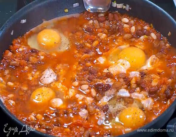 Когда выпарится лишний сок из помидоров, сделать в фасолевой массе углубления, разбить в них яйца, все посолить и поперчить.