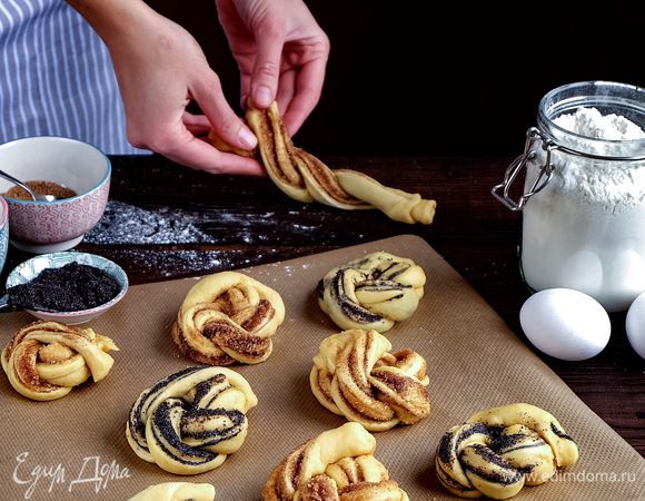 Формируем булочки. Раскатываем кусочек теста в прямоугольник примерно 20 см на 15 см. Маковую начинку просто тонким слоем размазываем по поверхности прямоугольника. Сворачиваем прямоугольник в плотный рулетик, взяв за основание более длинную сторону. Далее прямоугольник нужно разрезать вдоль, оставив один край неразрезанным. Получившиеся жгуты свернуть между собой и уже готовый жгут свернуть в кольцо, сформировав таким образом булочку. Для коричной булочки все манипуляции те же, только предварительно раскатанный прямоугольник теста нужно смазать кисточкой растопленным сливочным маслом, и затем на него сыпать сахар, смешанный с корицей.