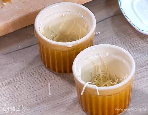 Небольшие керамические формы смазать оставшимся сливочным маслом и посыпать дно и стенки форм половиной натертого сыра.