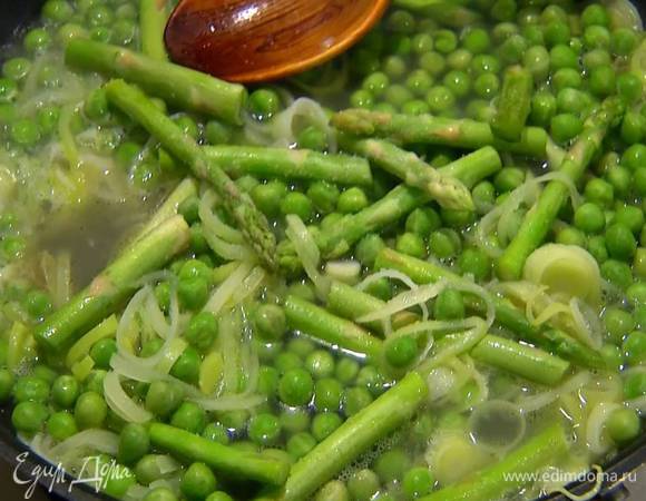 Добавить спаржу и зеленый горошек, влить овощной бульон и все посолить.