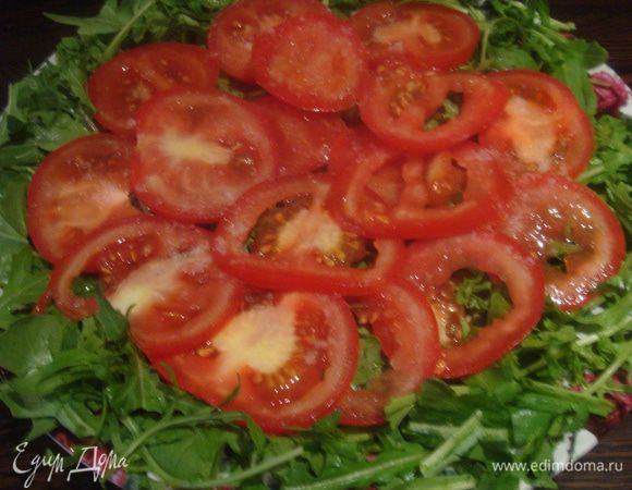Помидоры порезать на тонкие колечки, выложить на блюдо с руколой. Посолить.