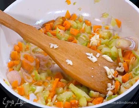 К моркови с сельдереем добавить лук и чеснок, посолить, перемешать и слегка обжарить на медленном огне.