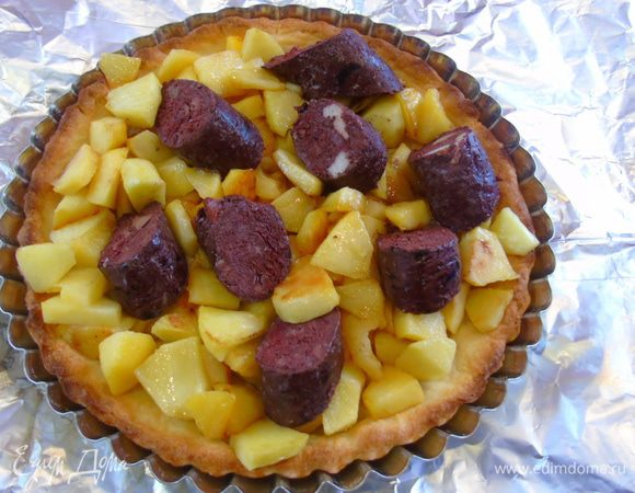 На корж выкладываем яблоки, а сверху слегка утопив нарезанную кусочками колбасу.