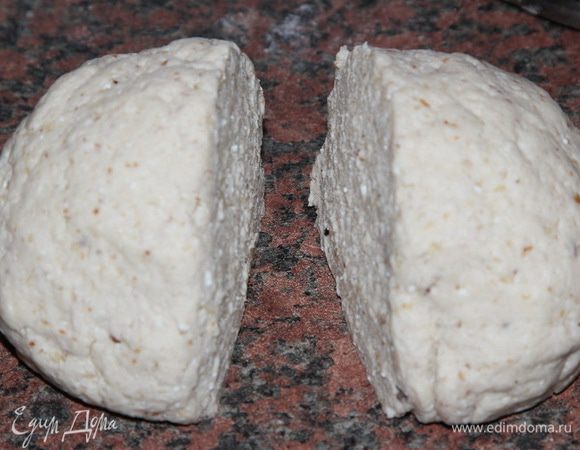 После этого добавляем полтора стакана муки и замешиваем мягкое и эластичное тесто так, чтобы комок не прилипал к рукам. Мне пришлось добавить еще пол-стакана муки, получилось всего 2 стакана. Может понадобиться меньше или больше: все зависит от влажности творога и от качества муки. Затем комок теста разрезаем пополам.