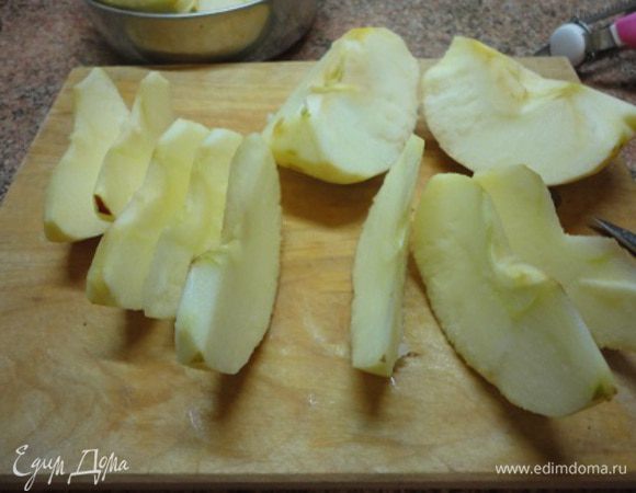 Включить духовку для разогрева до 180°С. Яблоки очистить от кожицы и сердцевины и нарезать тонкими дольками. 