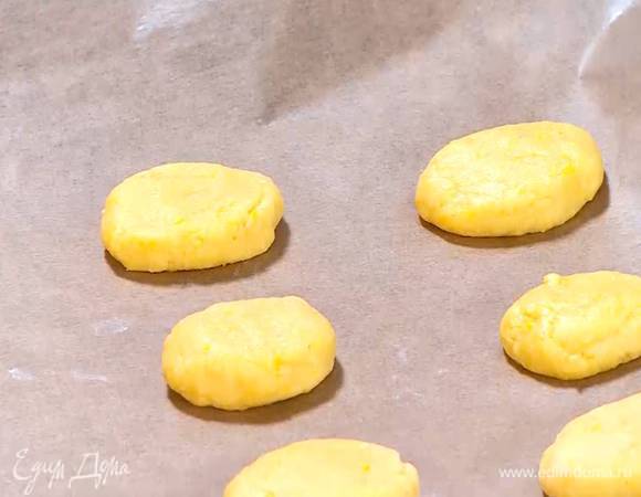 Сформировать из теста небольшие лепешки и выложить на противень, выстеленный бумагой для выпечки.