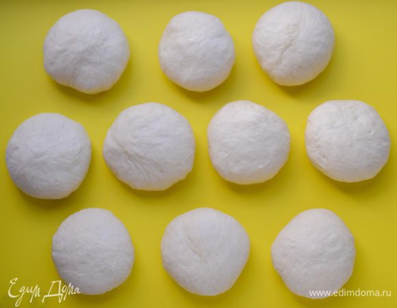 Подошедшее тесто хорошо обмять. Разделите на 10 равных частей (удобно это делать на весах), отщипывать фрагменты и скатывать в шарики. Заготовки накрыть смазанной растительным маслом пищевой пленкой, дать отдохнуть минут 15.