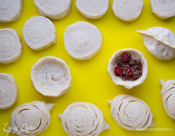 Начинка: вяленую вишню залить кипятком, оставить минут на 5. Промыть, обсушить на бумажном полотенце. Миндаль и грецкий орех измельчить в кофемолке (орехи могут быть любые, на ваш вкус), добавить сахар, кардамон (извлечь семена из коробочек, измельчить как можно мельче в ступке), хорошо взбитый белок (не обязательно, т. е. белок можно и не добавлять). Перемешать. Можно сразу соединить вишню с орехами, а можно добавлять по отдельности уже в заготовку, разницы нет. В традиционной бадамбуре вишни в начинке нет, но мне очень хотелось ягодной нотки, кислинки. Формовка. Положить получившийся маленький рулетик срезом на рабочую поверхность. Пальцами надавить посредине, формируя ямочку. В эту ямочку положить начинку. Края заготовки соединить, хорошо защипнуть, как у пирожков, но не тянуть сильно, чтобы не испортить рисунок слоев. Перевернуть заготовку швом вниз, придать форму. Нужно, чтобы получилась выпуклая лодочка.