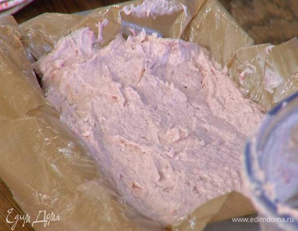 Форму для кекса выстелить бумагой для выпечки, смазанной оставшимся сливочным маслом, выложить тесто и разровнять его.