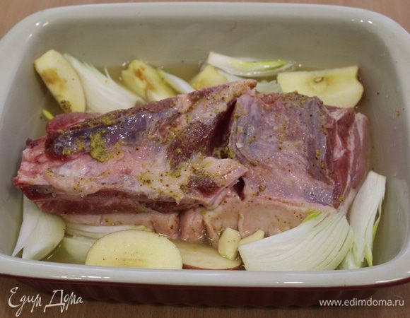 В форму налить воды, примерно около одного стакана и добавить пива. 
Выложить мясо шкуркой вниз. Разрезать лук и яблоки на 4 части, чеснок почистить. Выложить вокруг мяса.