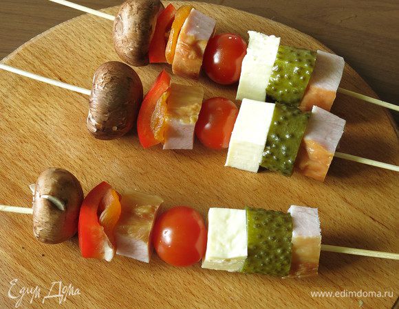 На выдержанные в воде шпажки надеваем начинку. Кусочек буженины и соленый вкус огурца, еще один кусочек мясного — сладость кураги, в центре — сочность сулугуни и томата.