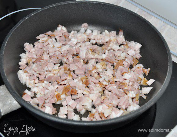 Бекон мелко порезать. На сухой разогретой сковороде, помешивая, обжарить на среднем огне бекон в течение 5-7 минут почти до хрустящего состояния. 
Переложить на тарелку, чтобы бекон немного остыл.