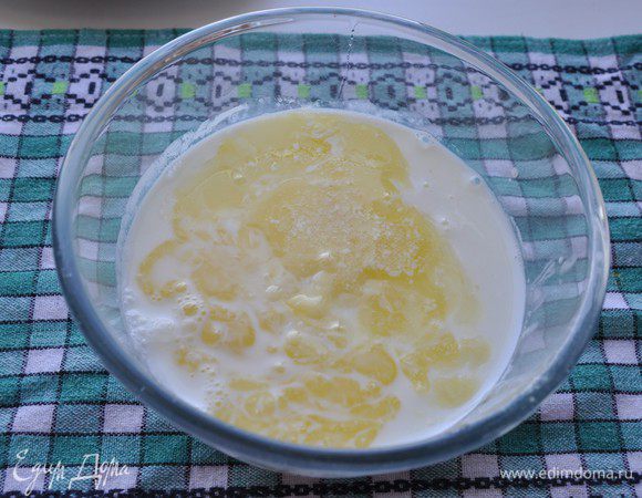 В отдельной миске смешать молоко, кефир, яйца и остывшее сливочное масло. Взбить венчиком. 