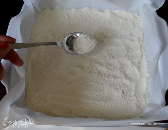 Форму размером 25х25 см проложить пекарской бумагой (или смазать немного маслом). Половину мучной смеси насыпать на дно формы, распределяя ровным слоем. 