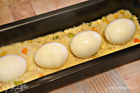 Сверху выложите половину кускуса, затем 4 сваренных яйца, и аккуратно, слегка приминая — оставшийся кускус. Накройте беконом и отправляйте в разогретую до 180°С духовку на 45 минут.