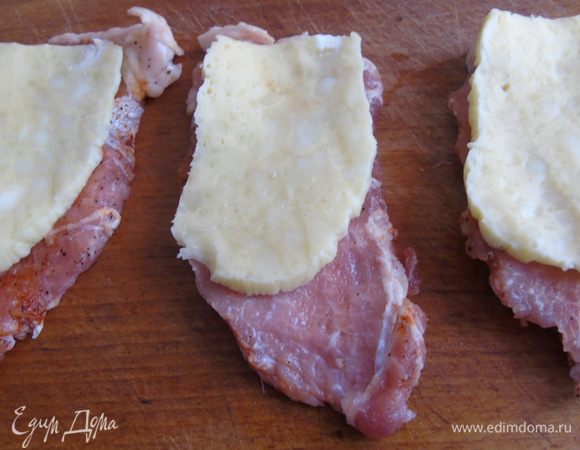 Мясо слегка отбейте рукояткой ножа, и поделите на половину. На одну половину мы будем класть начинку, а второй прикрывать. Сыр нарежьте пластинами и выложите поверх мяса.