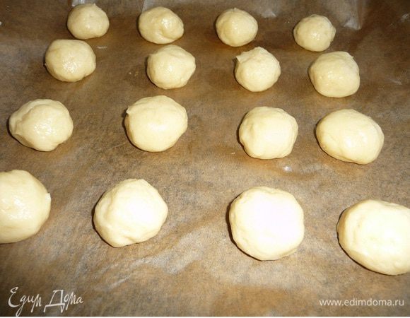 Руки смазать растительным маслом. Брать небольшое кол-во теста, скатать в шарик. Выкладывать на противень, застеленный пекарской бумагой на небольшом расстоянии друг от друга. При выпечки тесто увеличивается в объеме. У меня было 2 противня.