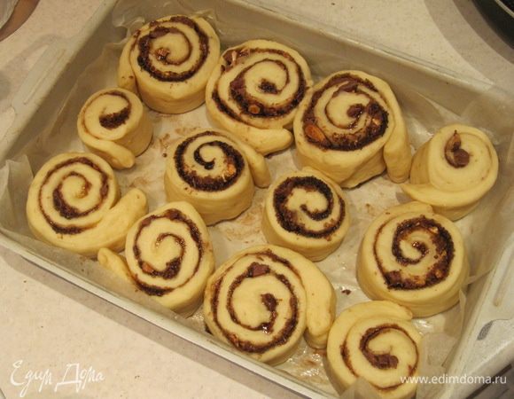 Форму для выпечки выстелить пергаментом и слегка смазать его сливочным маслом.
Поместить булочки в форму, накрыть пищевой пленкой и оставить на расстойку на 15-20 минут.