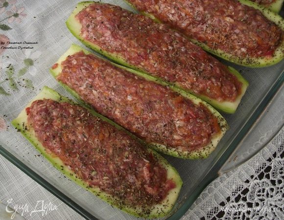 Мелко порезать лук, натереть на крупной терке морковь, мелко порезать помидор. На небольшом количестве масла припустить лук, затем добавить морковь, помидоры. Тушить 2-3 минуты. Посыпать прованскими травами. Фарш приправить солью и смесью перцев по вкусу, добавить щепотку мускатного ореха, немного коньяка. Хорошо перемешать фарш. Тушеные овощи добавить к фаршу и перемешать. Наполнить половинки кабачков так, чтобы фарш полностью покрывал всю половинку. Выложить кабачки в форму, смазанную маслом.