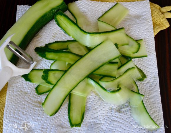 Длинные (голландские) огурцы вымыть и с помощью овощерезки нарезать тонкими лентами (не доходя до середины с семенами). Выложить на салфетку и промокнуть. 