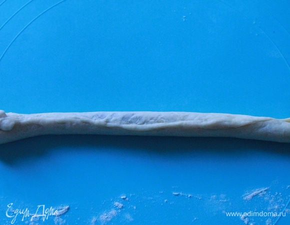 Берем кусочек белого теста и также раскатываем из него тонкую полоску. Выкладываем на нее нашу темную колбаску и защипываем края. Получается вот такая толстенькая колбаска. Я ее делала длиной равной форме 20 см.