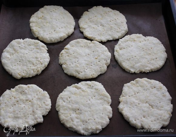 Сформировать руками лепешки толщиной около 1 см. Наколоть вилкой и выложить на выстеленный бумагой для выпечки противень.