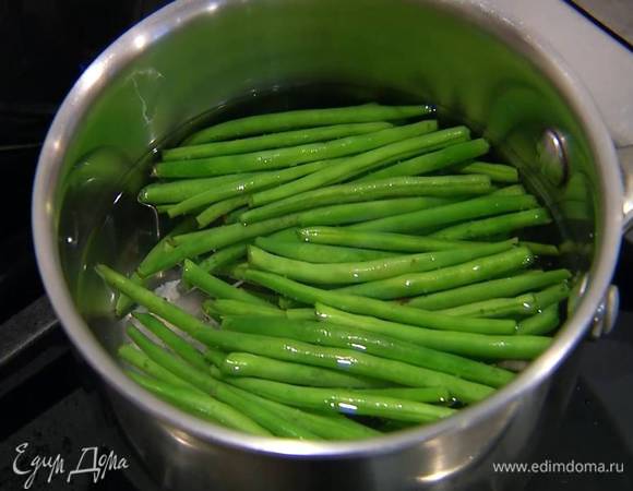 Стручковую фасоль отварить в кипящей воде, затем слить и обдать фасоль ледяной водой.