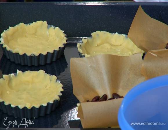 Из бумаги для выпечки вырезать круги или квадраты по количеству и размеру тарталеток, выложить бумагу на тесто и насыпать сверху фасоль.