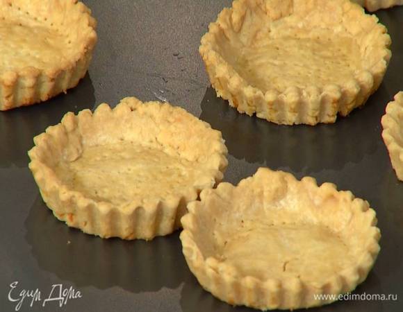 Выпекать тарталетки в разогретой духовке 20 минут, затем удалить фасоль с бумагой и дать тарталеткам остыть.