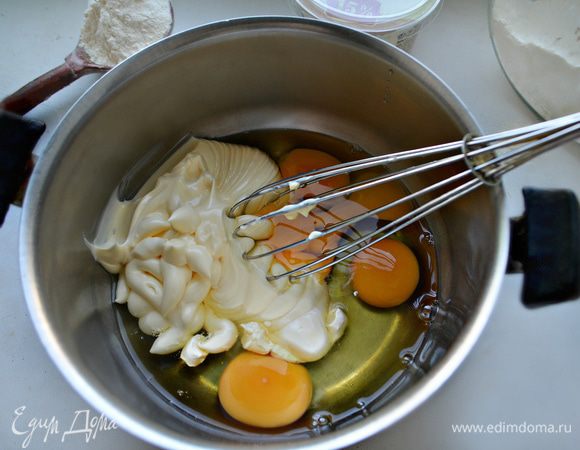 В кастрюльку вбейте яйца, добавьте сметану и майонез. Хорошо все взбейте с помощью венчика. Затем, порциями, добавьте муку, предварительно просеянную вместе с разрыхлителем, и перемешайте. Должно получиться тесто, по консистенции напоминающее густую сметану.