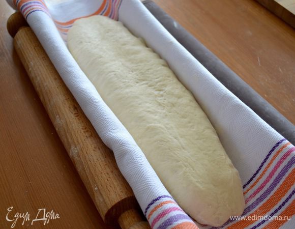 Подготовьте льняное полотенце, слегка присыпьте его мукой и выложите на него хлеб "раздавленной" стороной вниз! Именно поэтому удобнее это сделать, помогая себе ковриком, приподняв за концы и перевернув хлеб на полотенце (просто первый раз переложить хлеб со стола мне было сложнее, не повредив форму сформированной буханки). По обеим сторонам зафиксировать форму буханки, чтобы она не расползлась в течение последней перед выпечкой расстойки хлеба. Последний раз накройте хлеб полотенцем и оставьте на минут 20-30 до увеличения объема вдвое. 